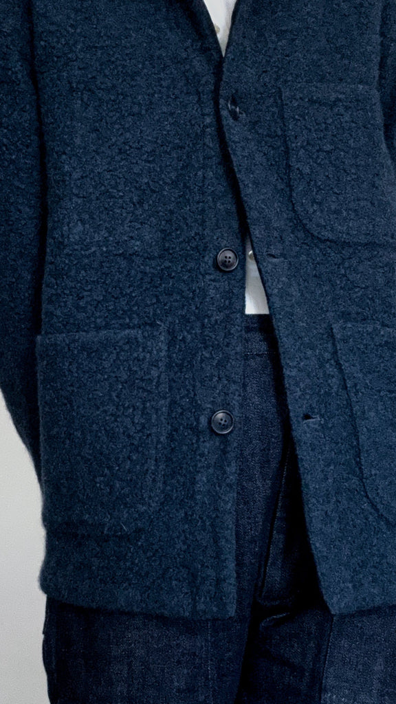 Navy blue textured jacket with button details on a light gray background