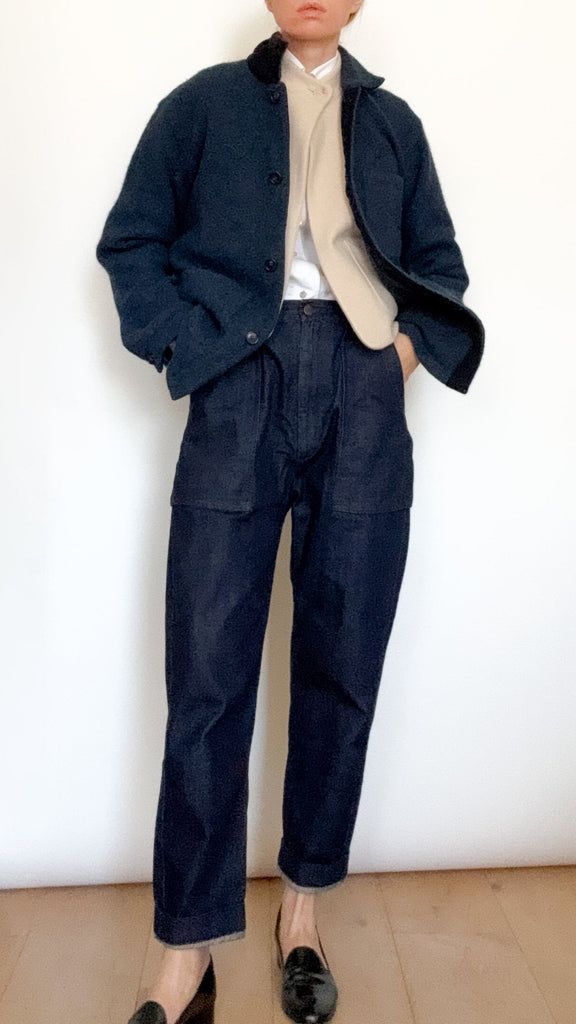 Person wearing a dark blue coat and jeans against a white background