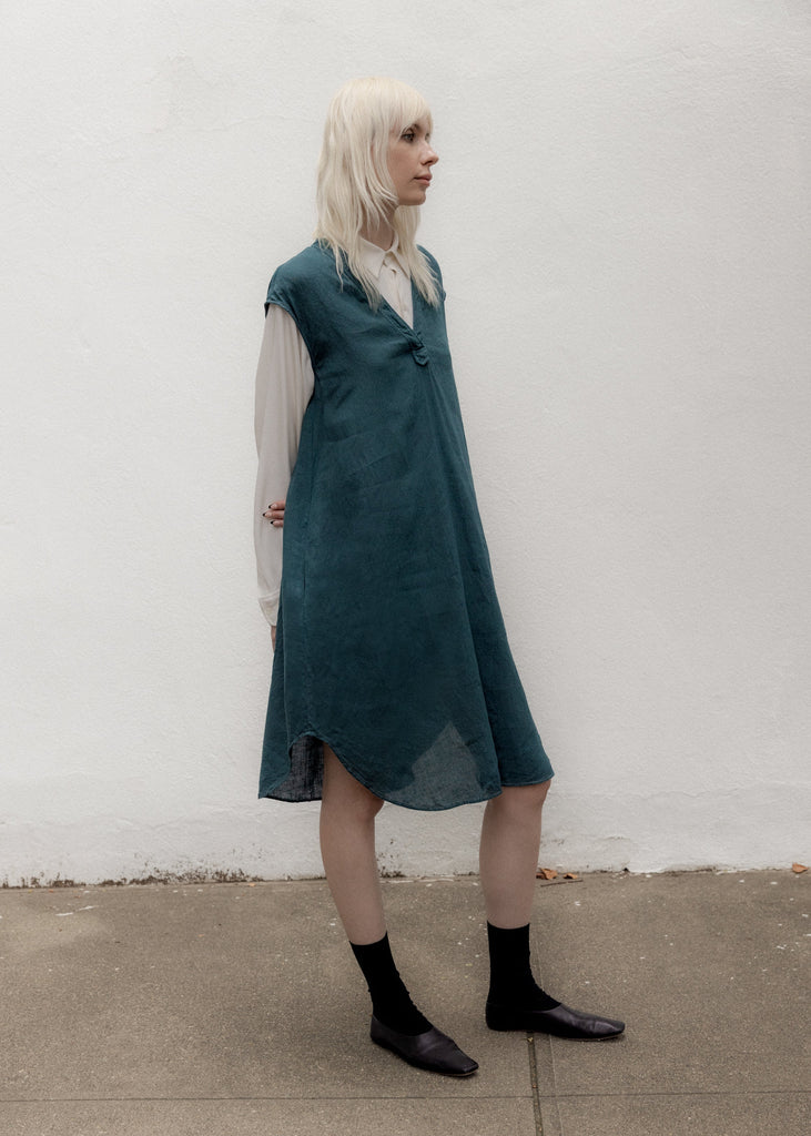Person wearing a teal dress against a white wall