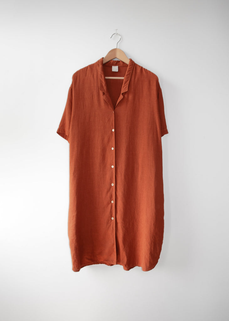 Copper shirt dress on a hanger against a white background