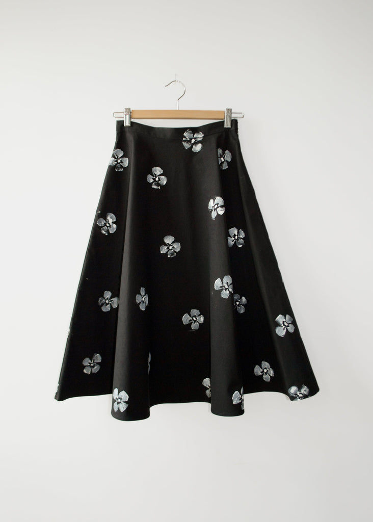 Black skirt with floral patterns on a hanger against a white background
