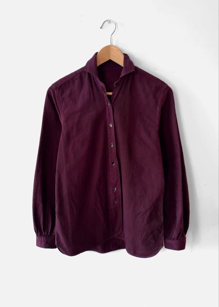 Burgundy cotton shirt on a wooden hanger against a white background