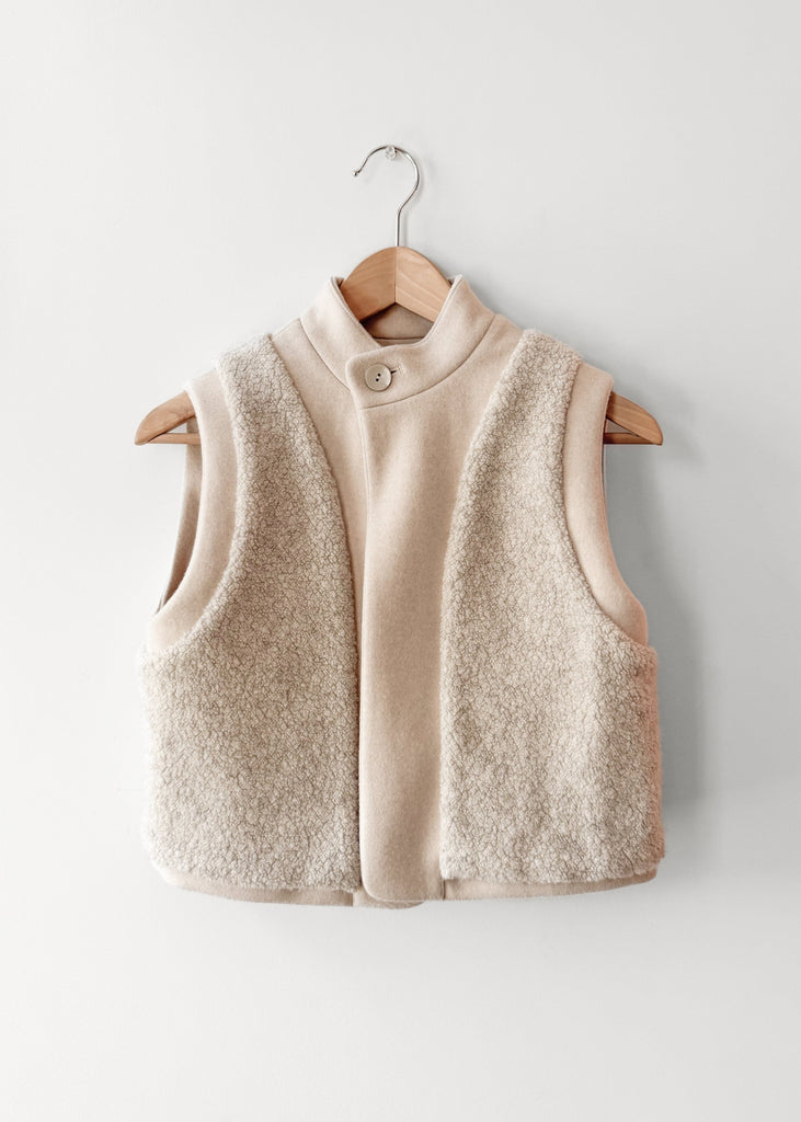 Beige wool pile vest on a wooden hanger against a white background