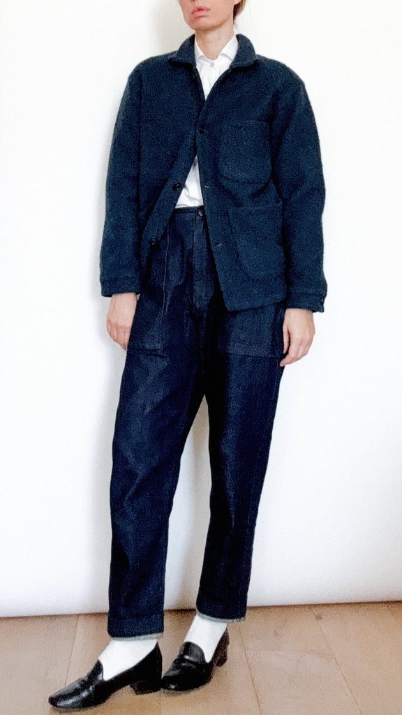 Person wearing a navy blue outfit with a white shirt against a plain background