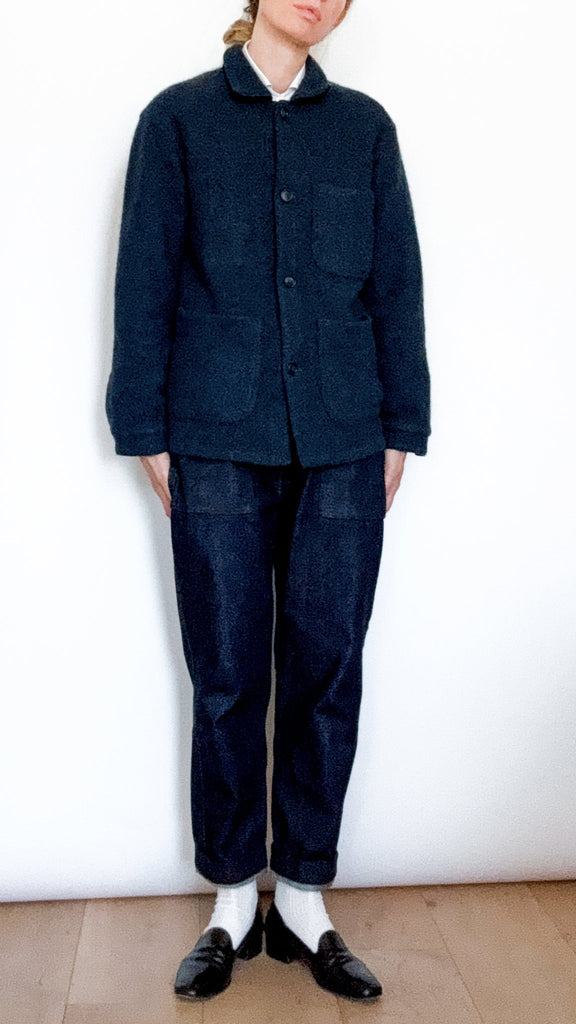 Person wearing a navy blue jacket and pants against a white background