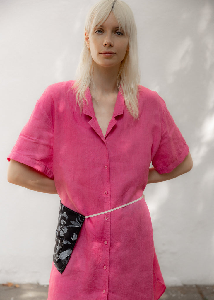 Person wearing a bright pink shirt with a plain background