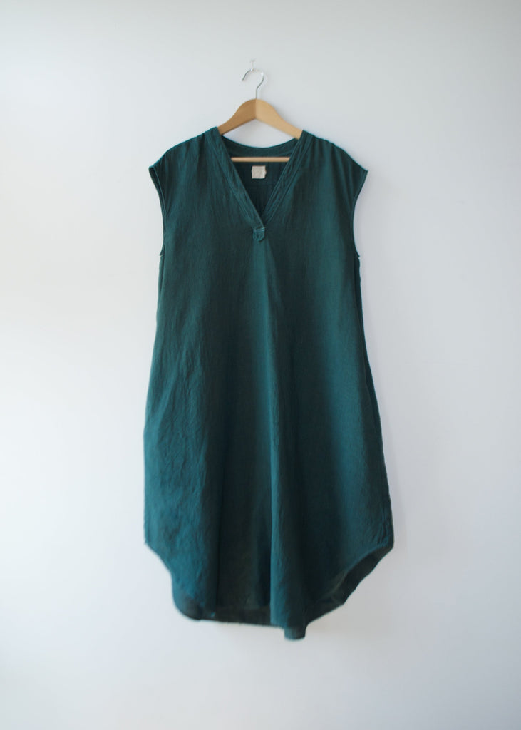 Green sleeveless dress on a hanger against a white background